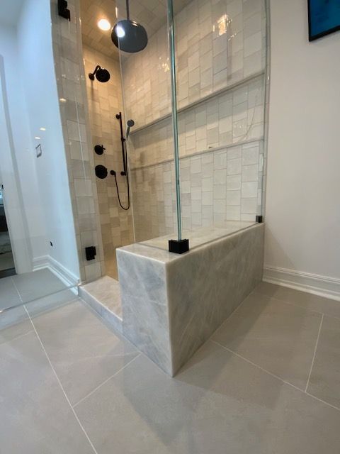 A bathroom with a walk in shower with a glass door