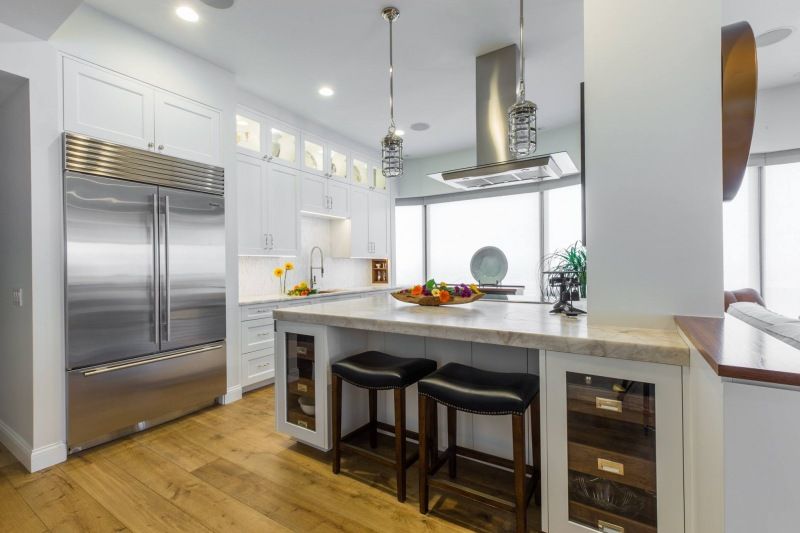 A kitchen with stainless steel appliances , white cabinets , hardwood floors and a large island.