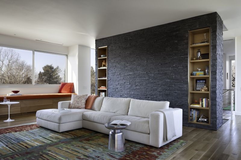 A living room with a white sectional couch and a brick wall