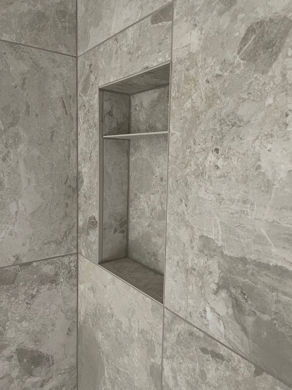 A close up of a shower niche in a tiled wall.