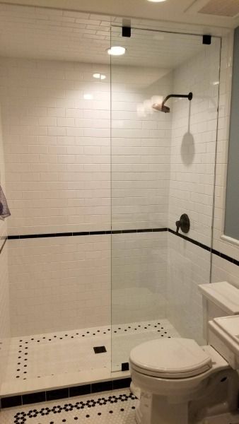 A bathroom with a toilet , shower , and mirror.