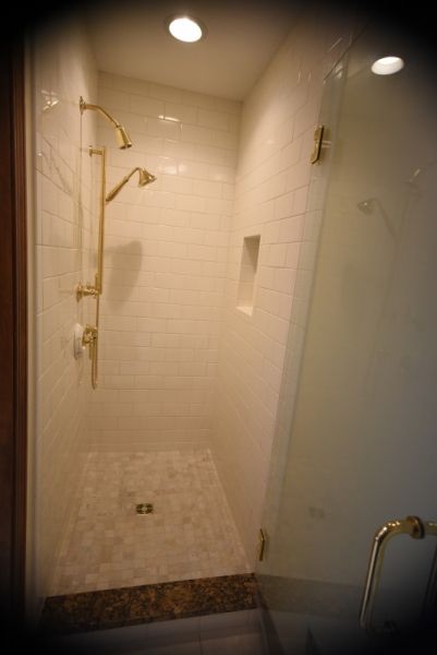A bathroom with a walk in shower and a glass door.