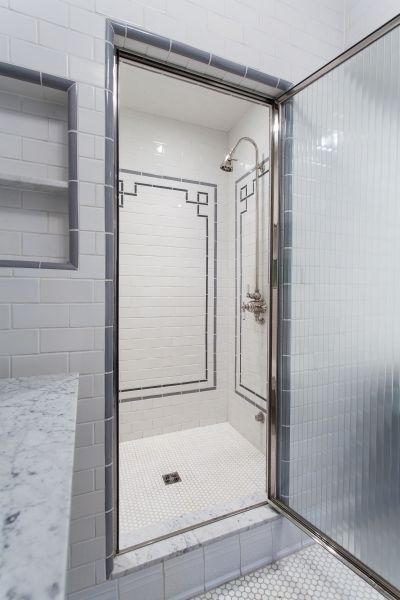 A bathroom with a walk in shower and a glass door.