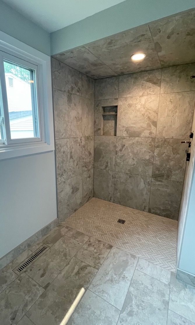 A bathroom with a walk in shower and a window.