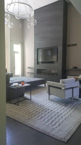 A living room with a fireplace , chairs , a rug and a television.