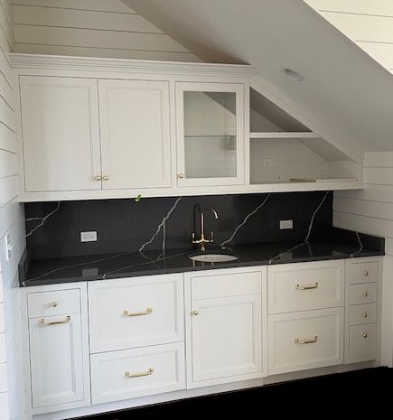 A kitchen with white cabinets and black counter tops