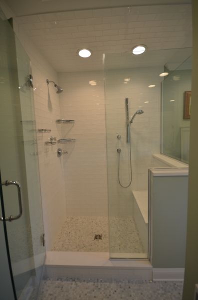 A bathroom with a walk in shower and a bench