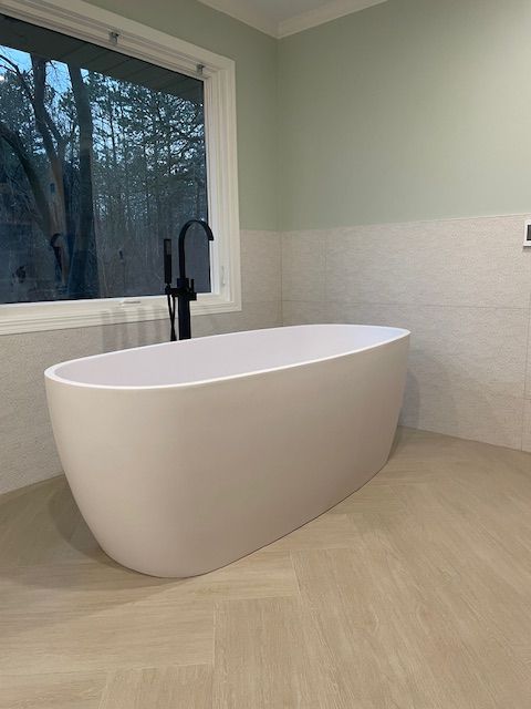 A white bathtub is sitting in a bathroom next to a window.