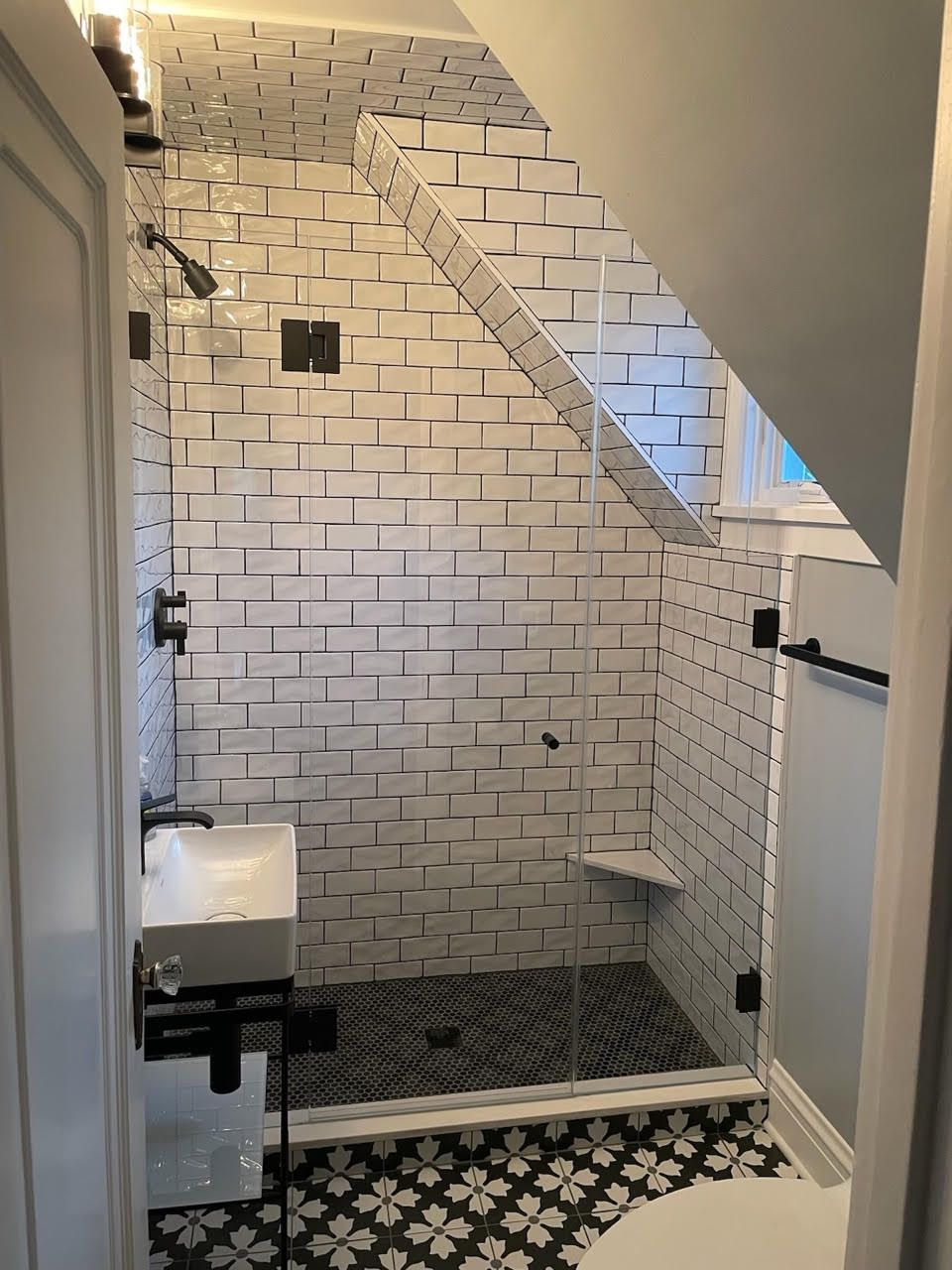 A bathroom with a walk in shower and a sink