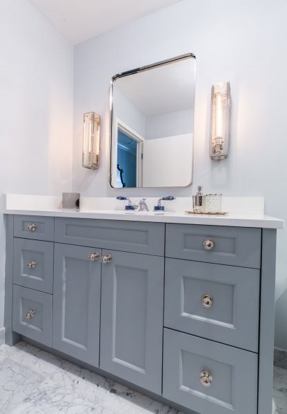 A bathroom with blue cabinets and a large mirror