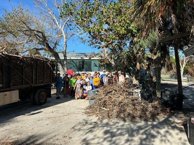 A group of people are standing in front of a dump truck.