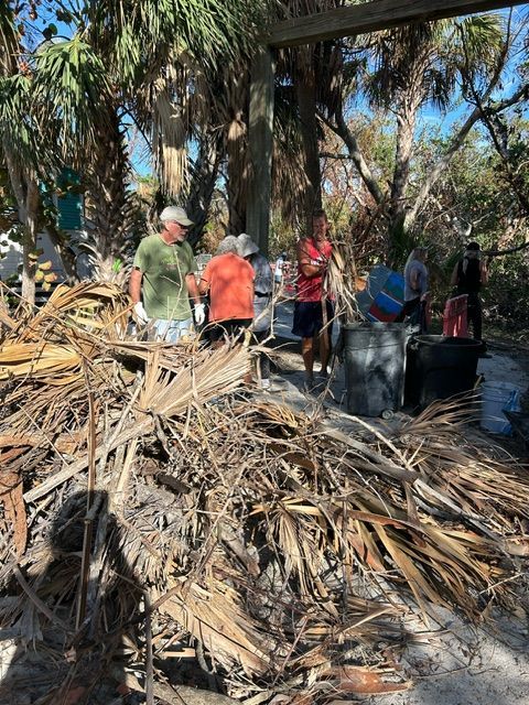 A group of people are standing around a pile of wood.