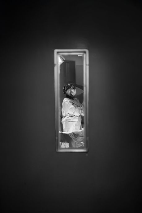 Una fotografía en blanco y negro de una persona parada frente a un espejo.