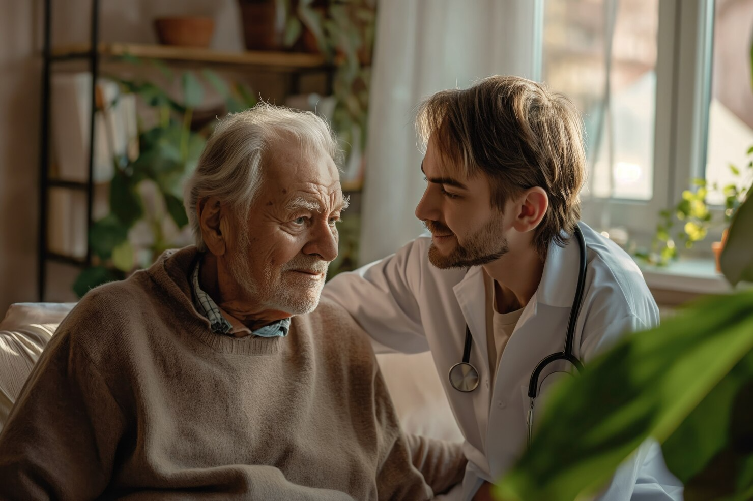 A doctor is talking to an elderly man on a couch.