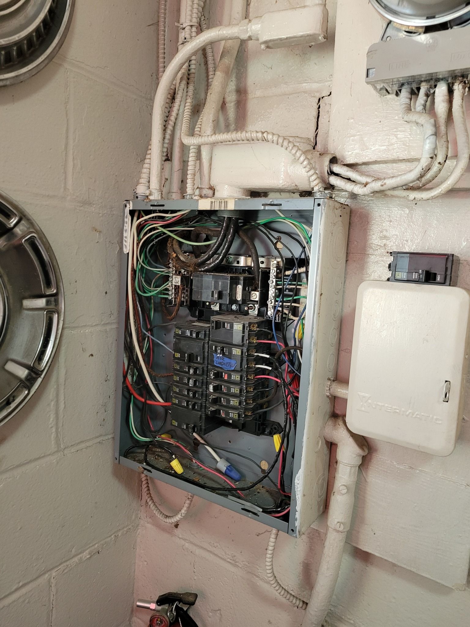 Open electrical panel on a concrete wall with exposed wires.
