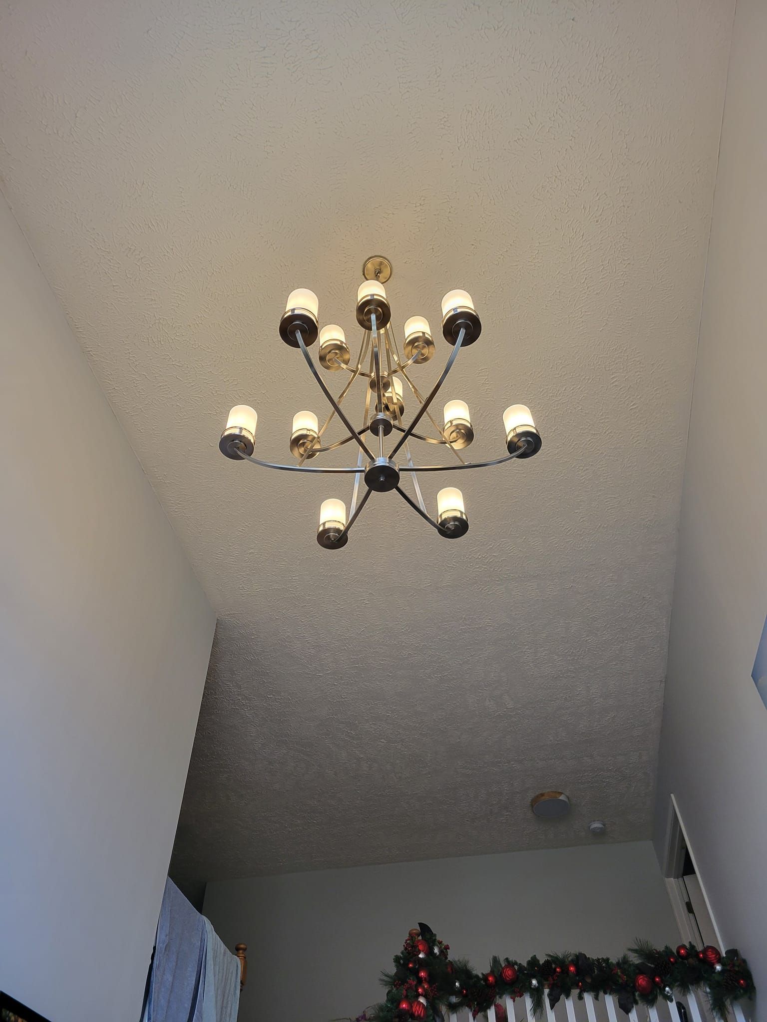 A multi-light chandelier hangs from a textured white ceiling in a home's entryway.