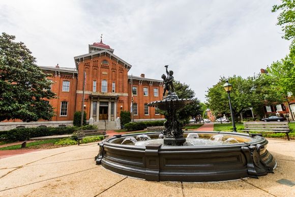 A large brick building with a fountain in front of it.