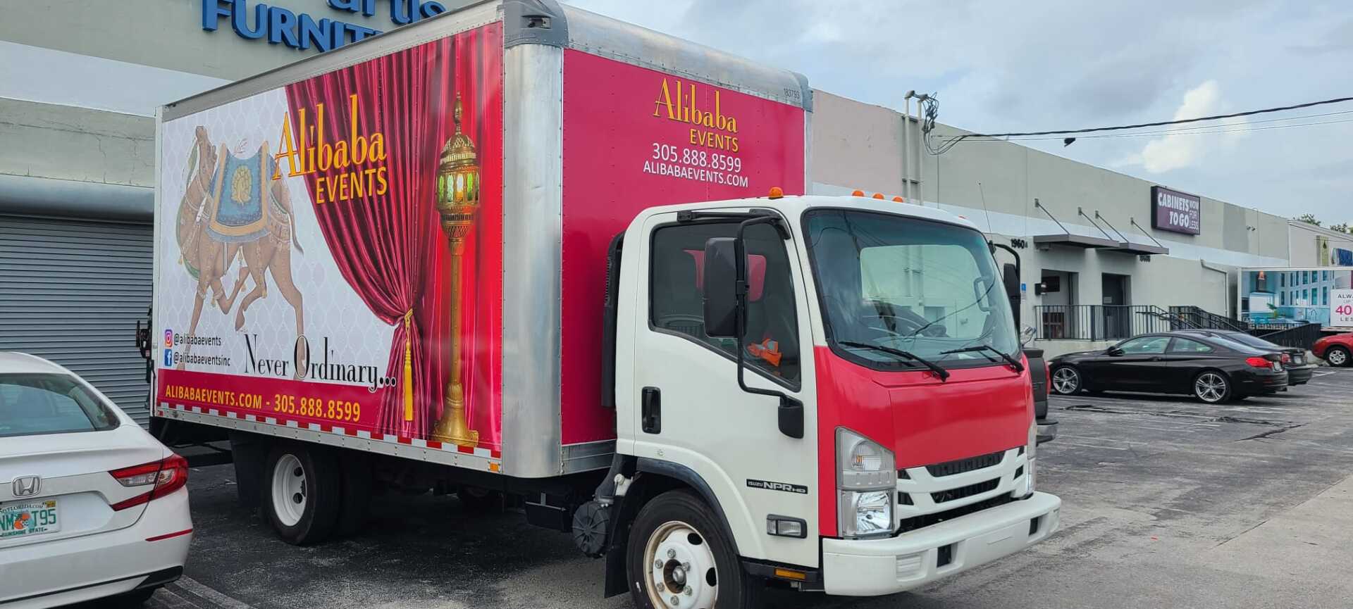 A red and white truck is parked in a parking lot in front of a building.