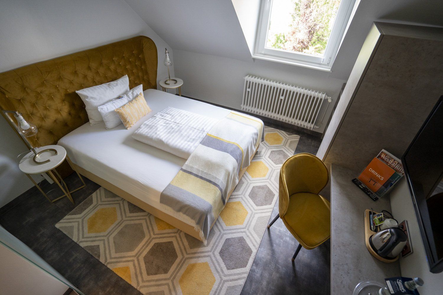 Ein Hotelzimmer mit Bett, Stuhl, Schreibtisch und Fenster.