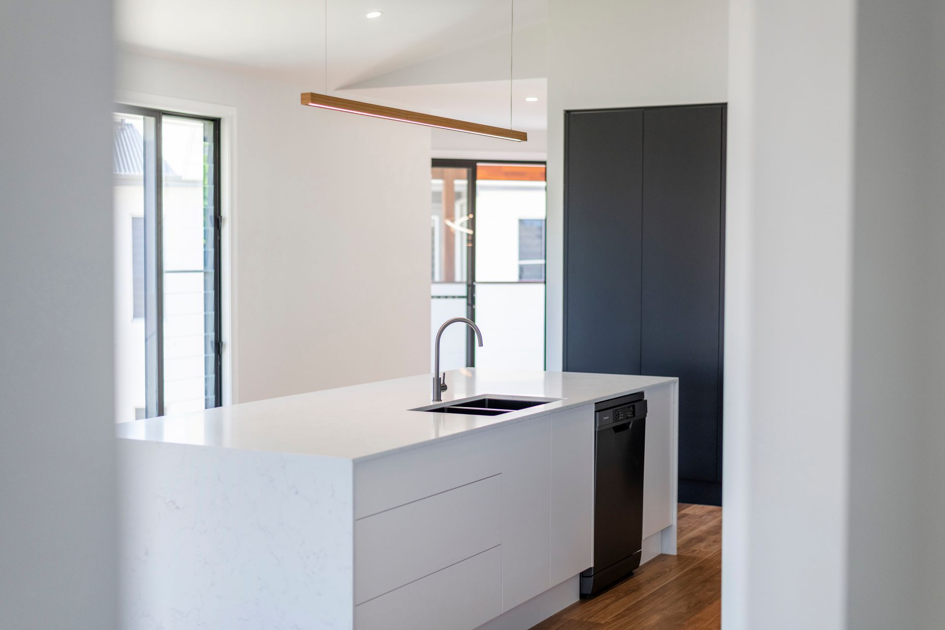 Modern kitchen with white island, black faucet, and dark cabinets.
