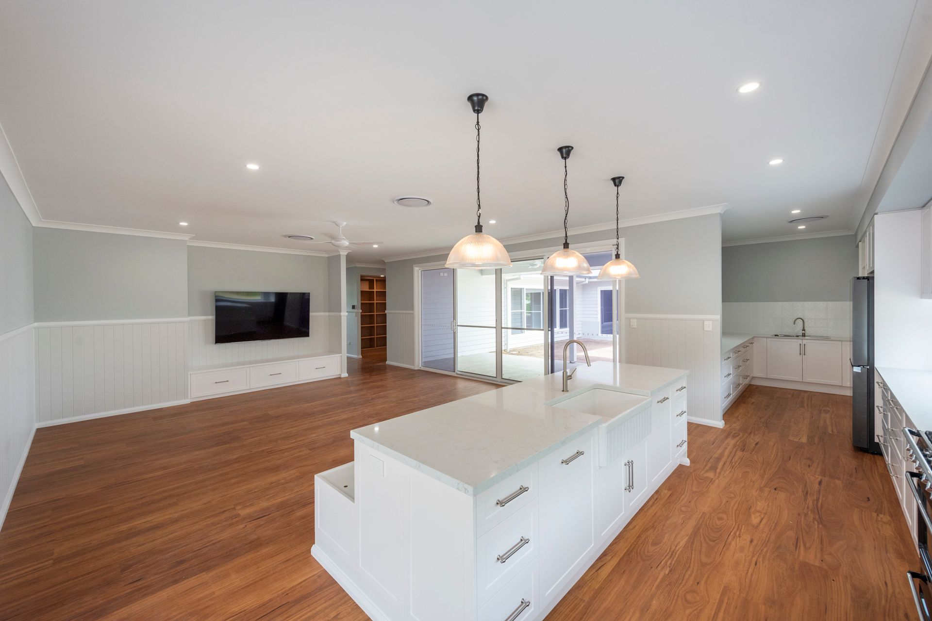 Open-plan kitchen and living area with white island, wooden floors, and light blue walls.