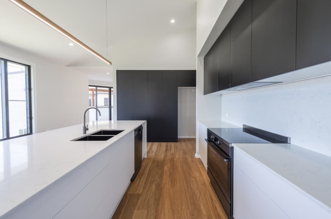 A Kitchen With Black Cabinets , White Counter Tops And Wooden Floors — Content Stone In Coffs Harbour, NSW