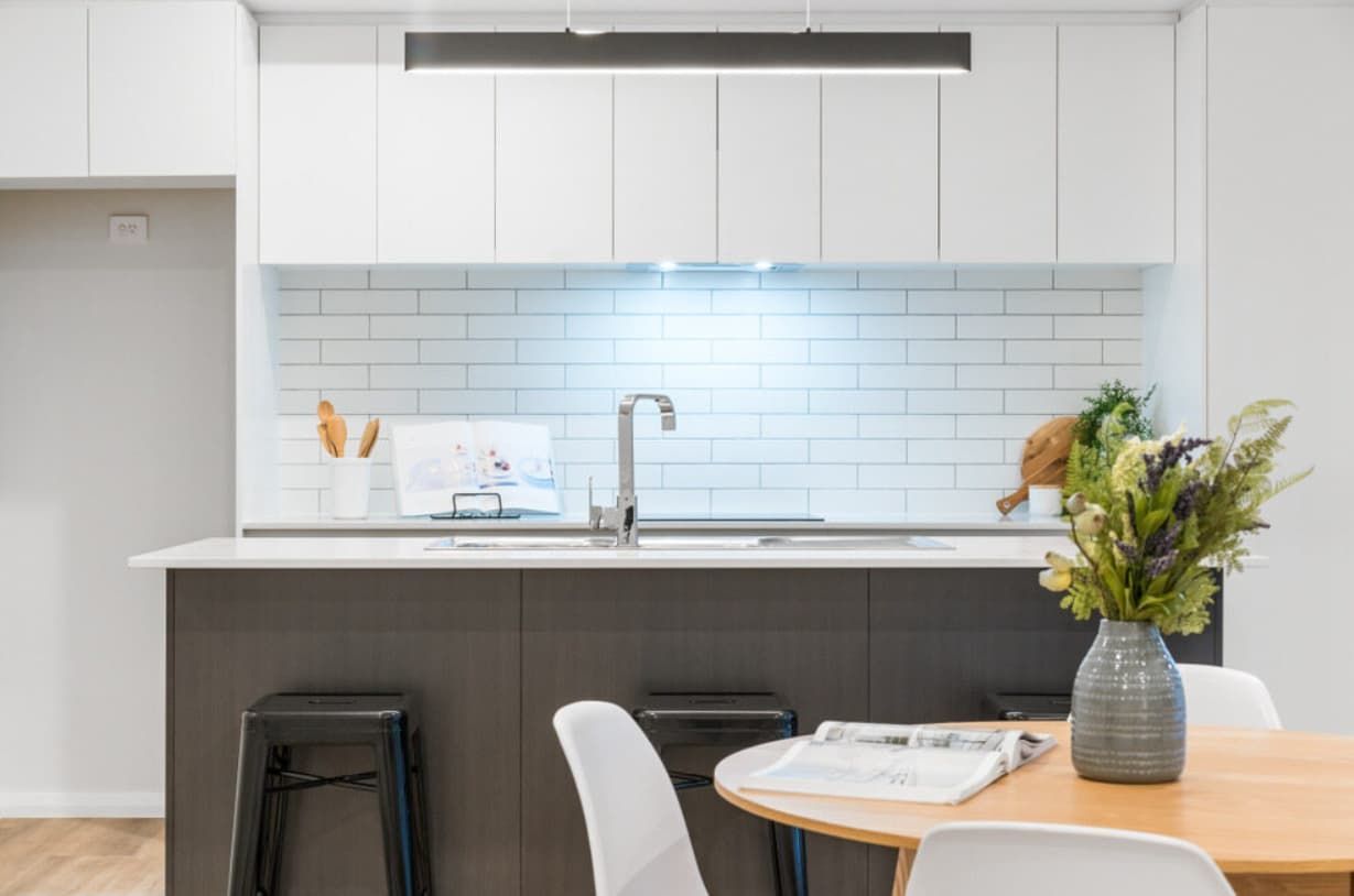 A Kitchen With A Table And Chairs And A Vase Of Flowers On The Counter — Content Stone In Lismore, NSW