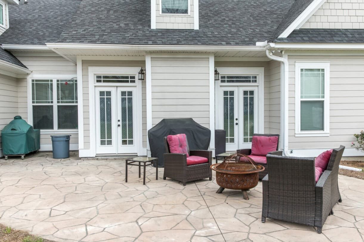 A Patio With Furniture And A Fire Pit In Front Of A House — Content Stone In Glen Innes, NSW