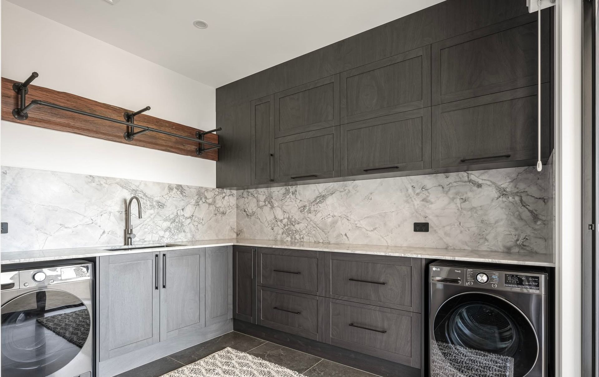 A Kitchen With Dark Cabinets, washing machine And A sink— Content Stone In Trenayr, NSW