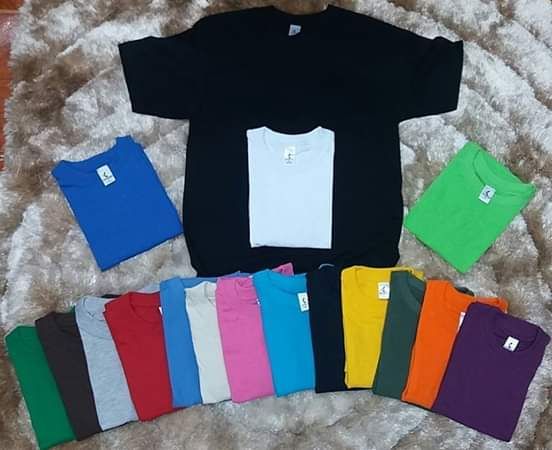 Un montón de camisetas de diferentes colores están sobre una alfombra.