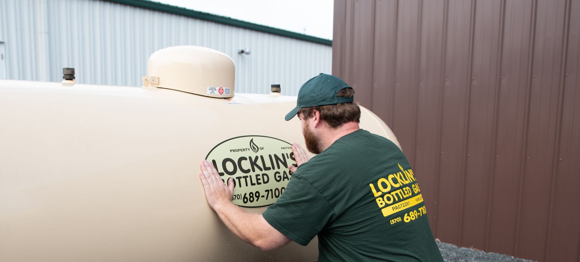 A man in a green shirt is working on a large tank.