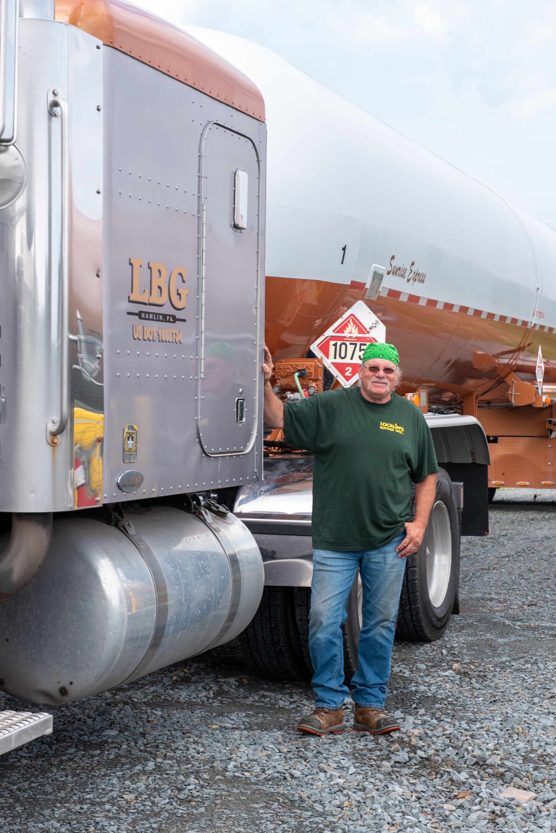 A man is standing in front of a semi truck holding a stop sign.