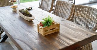 A wooden table with wicker chairs and a wooden crate on it.