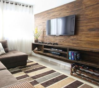 A living room with a couch and a flat screen tv on the wall.