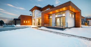 A modern house with a lot of windows is covered in snow.