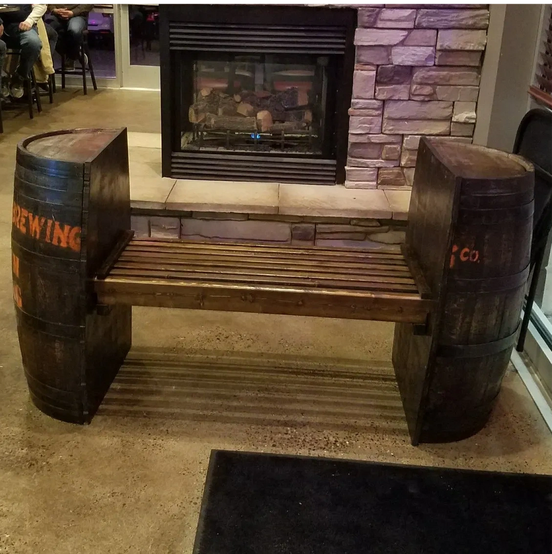 A wooden bench made out of barrels with the word brewing painted on them