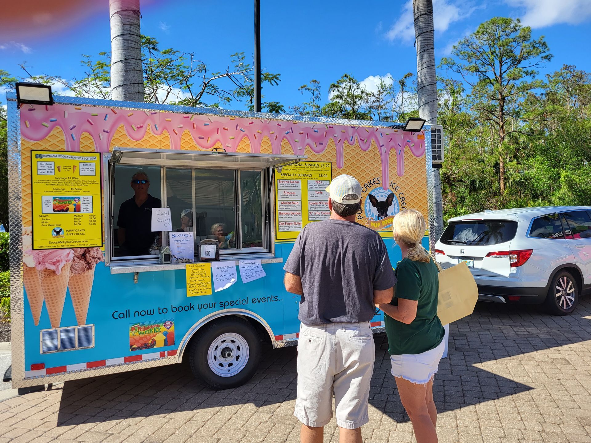 Ice cream truck with customers; blue and pink paint, man serving.