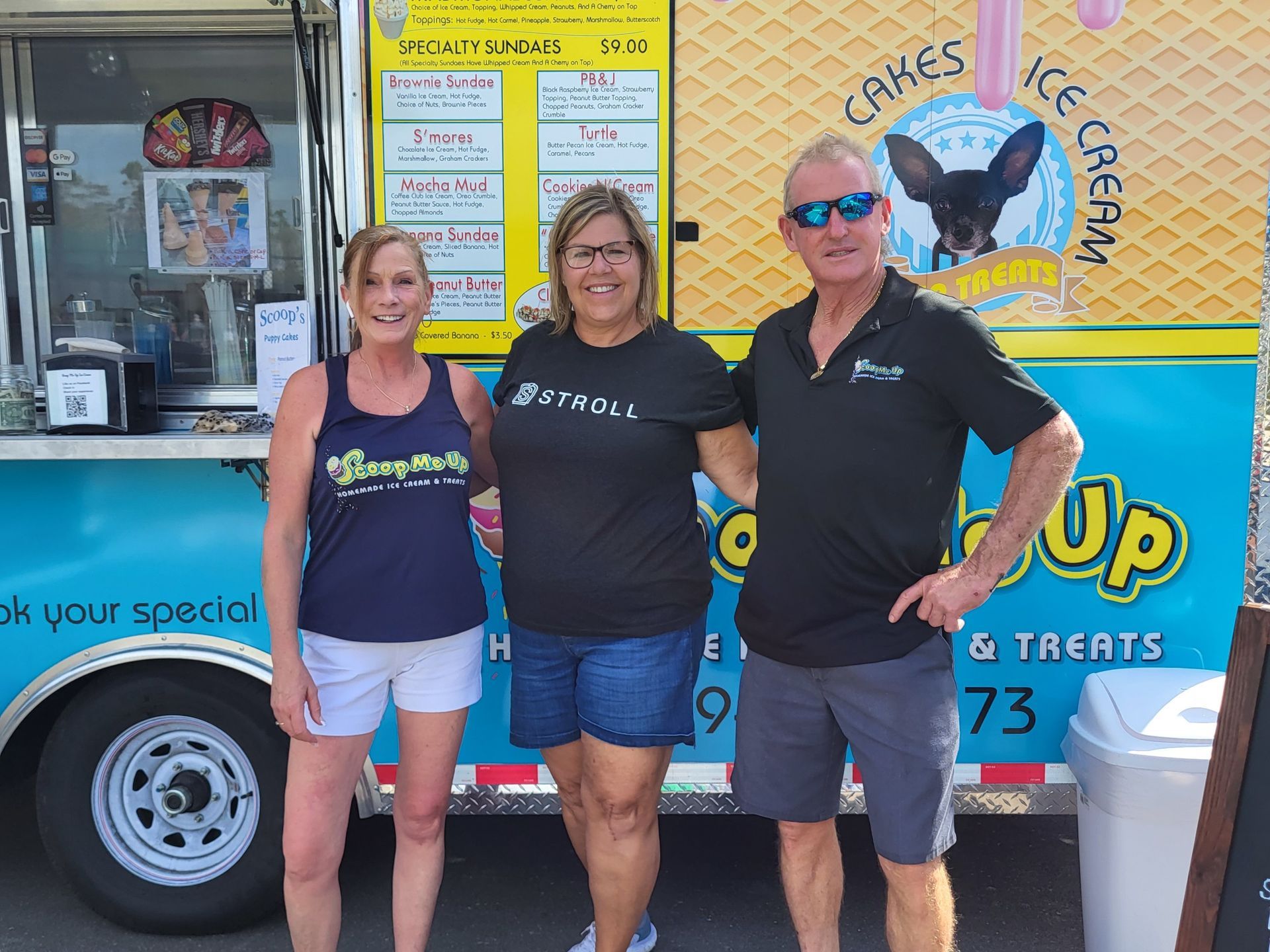 Three people pose in front of an ice cream truck with a dog logo.