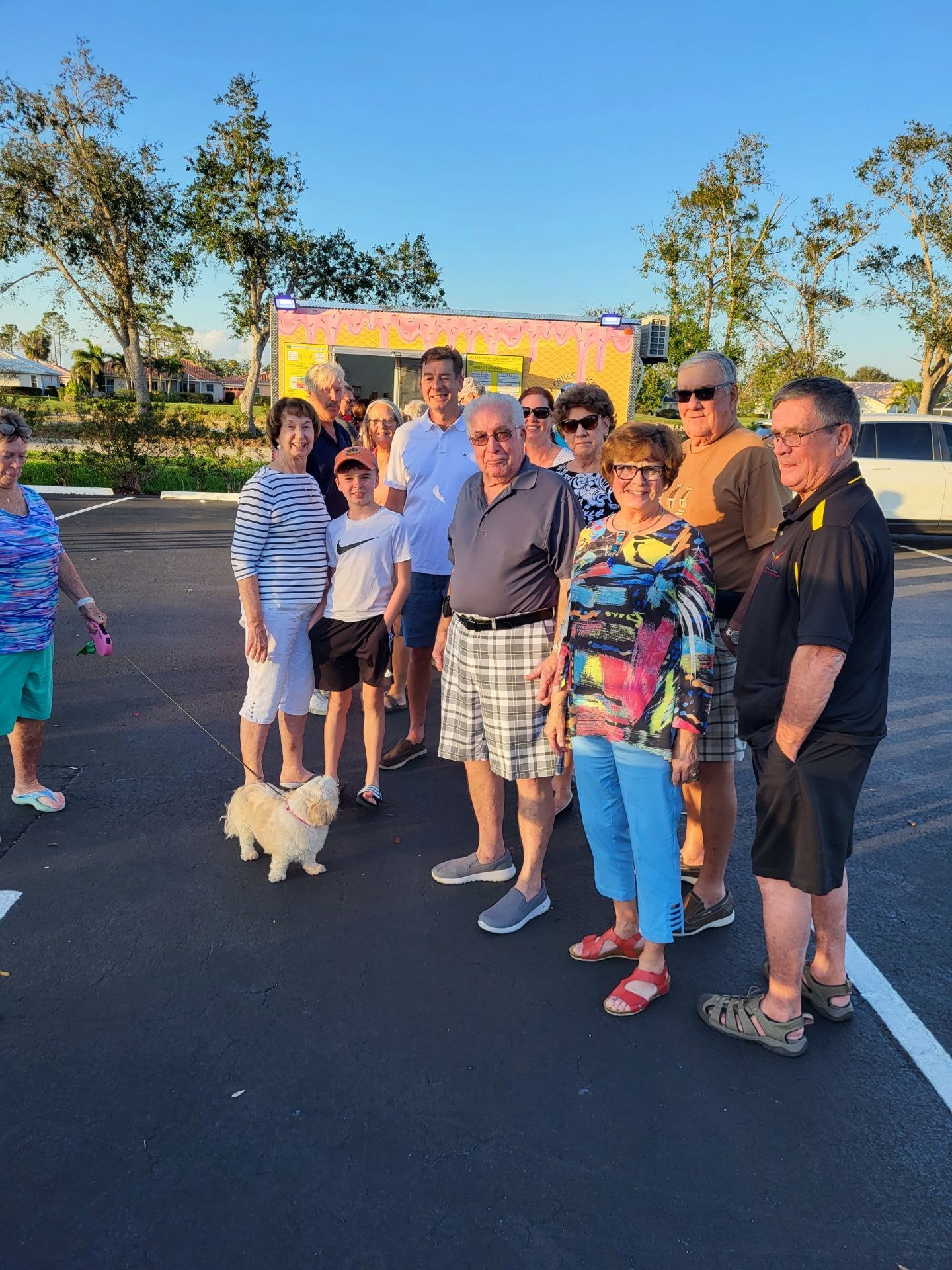 Group of people in a parking lot with a food truck in the background; some are smiling.