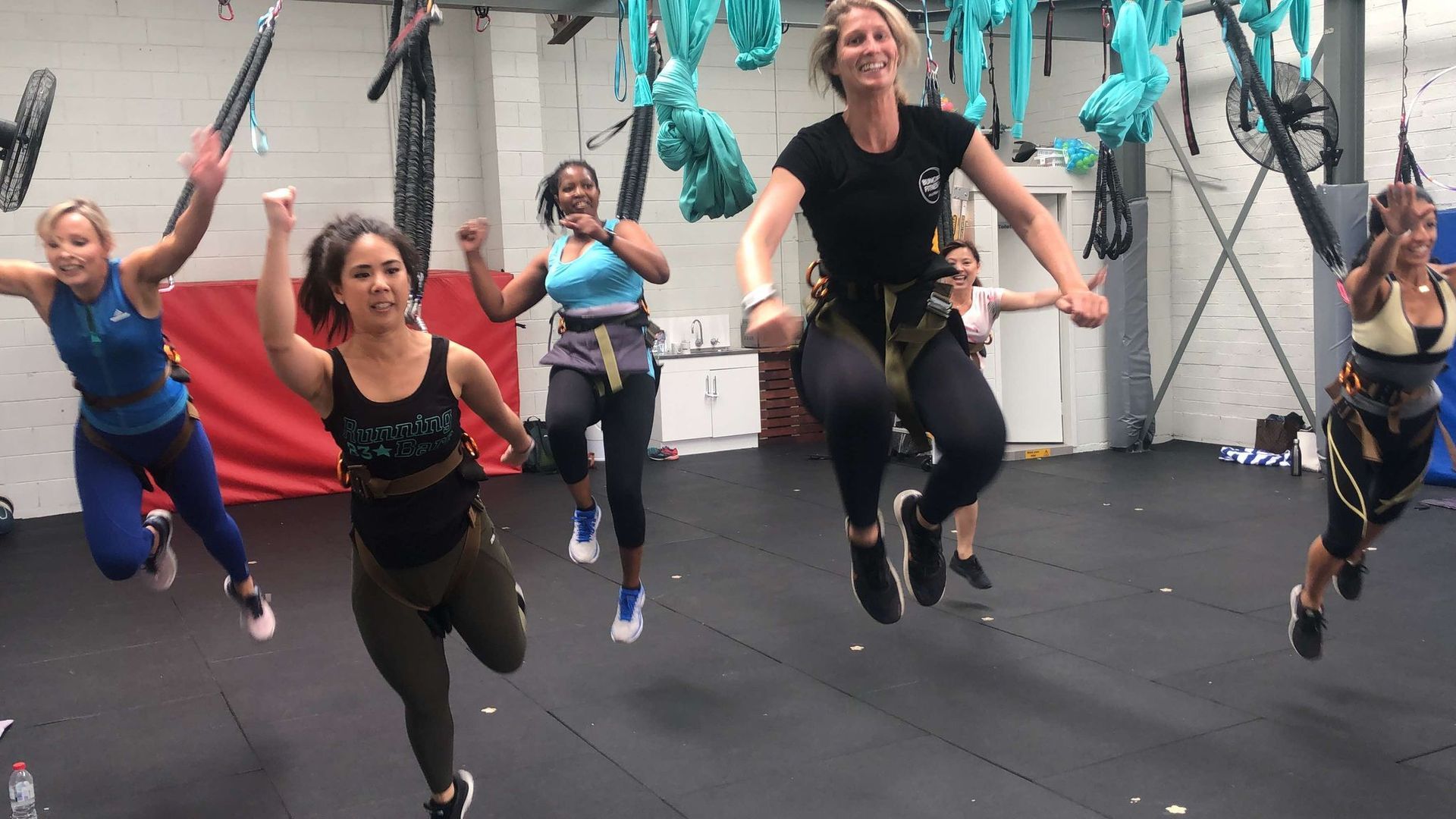 A group of women are jumping in the air in a gym.