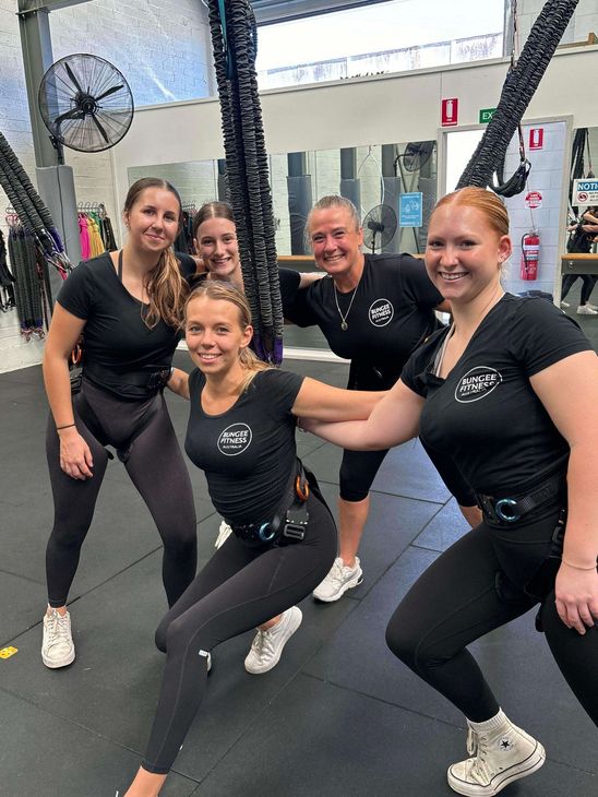 A group of women are posing for a picture in a gym.