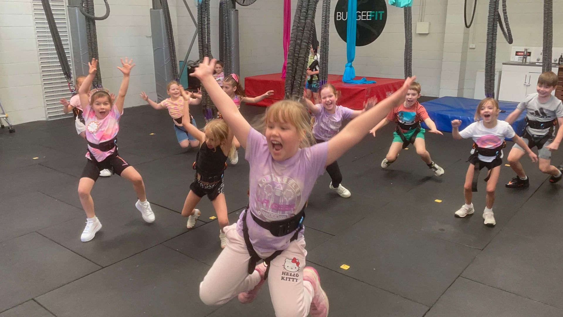 A group of children are jumping in the air in a gym.