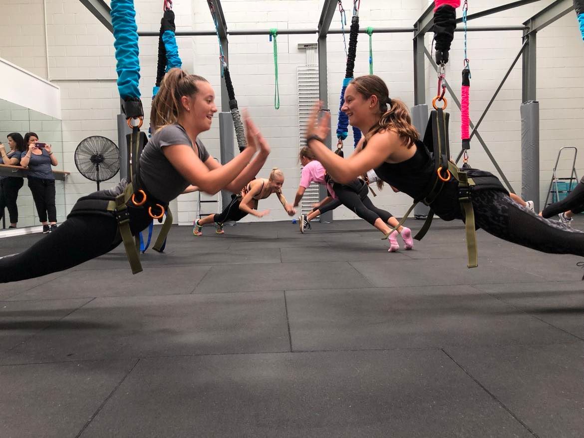 A group of women are doing aerial yoga in a gym.