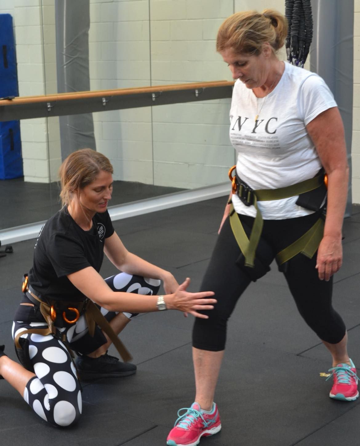 A woman in a nyc shirt is helping another woman stretch