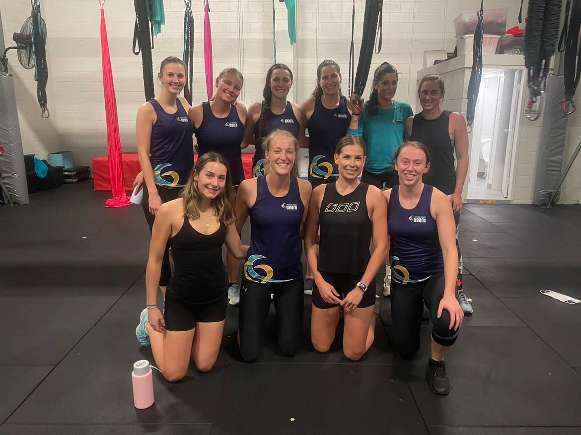 A group of women are posing for a picture in a gym.