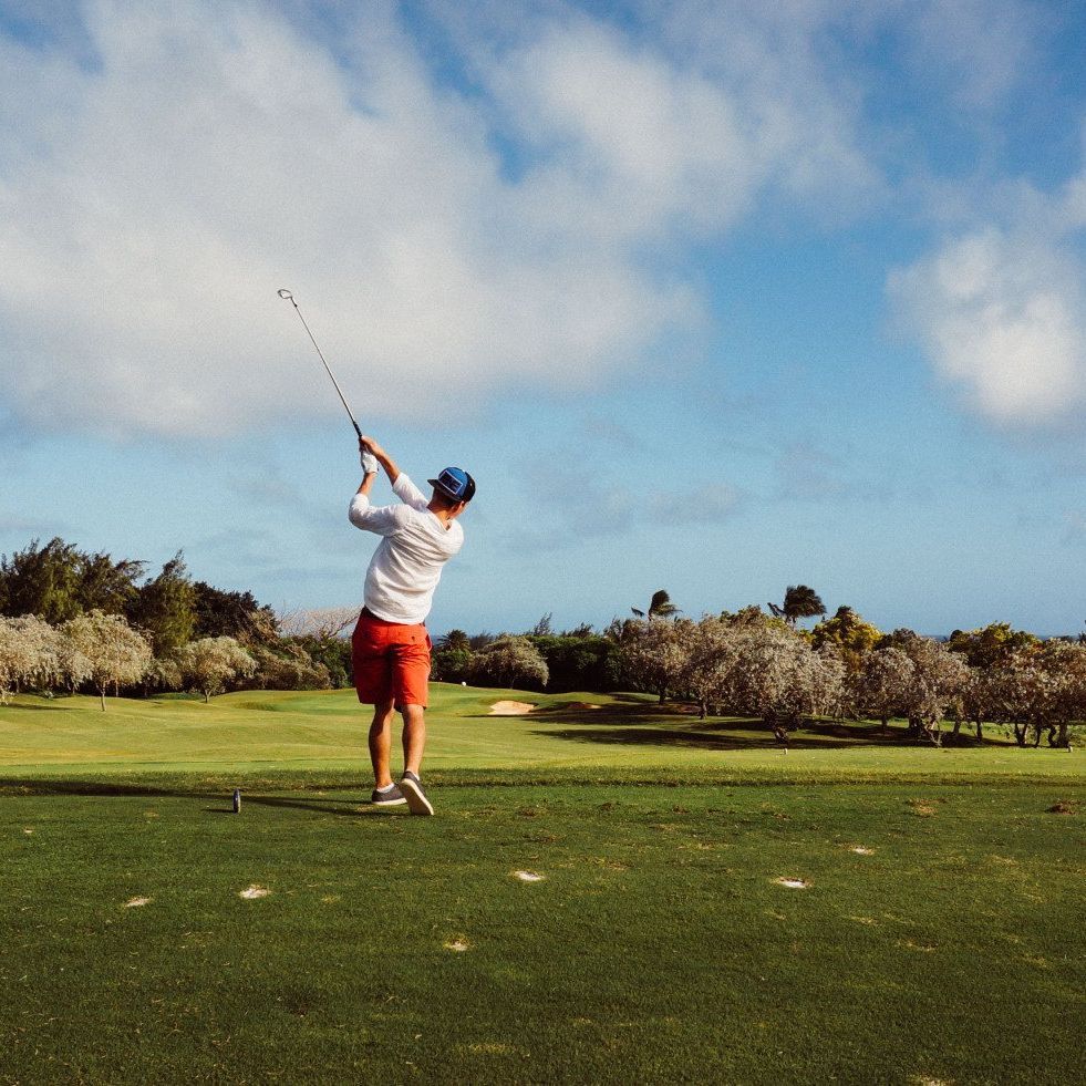 A man is swinging a golf club on a golf course