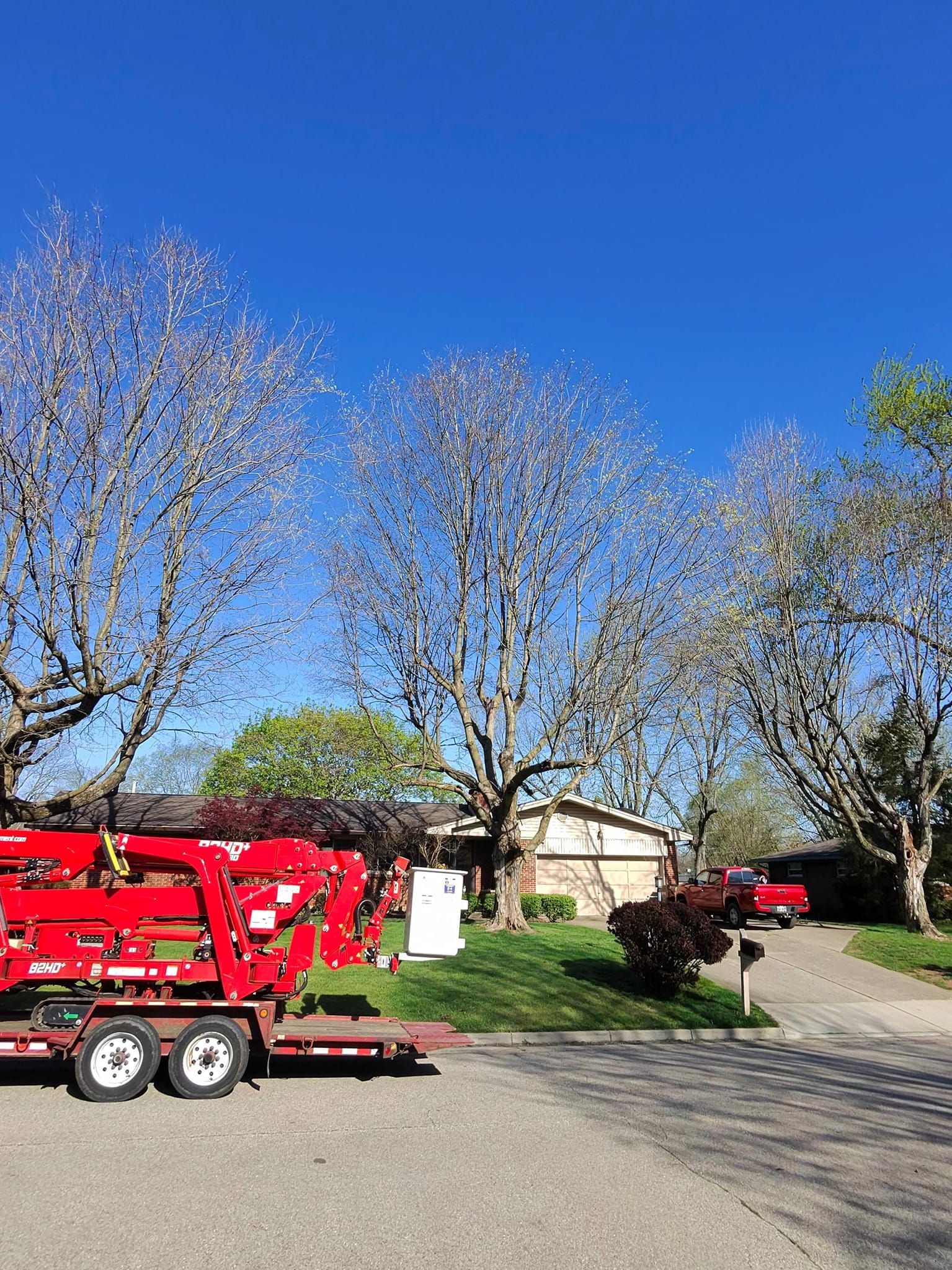 A red crane is parked on the side of the road in front of a house.