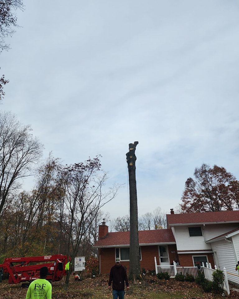 A man in a green shirt is standing in front of a house.