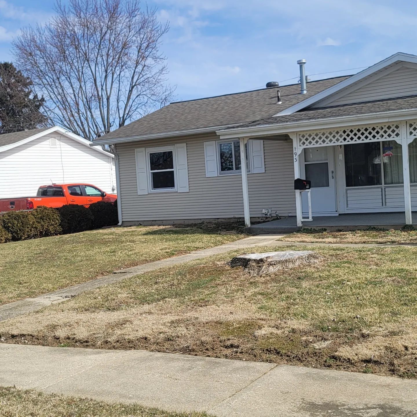 A house with a porch and a red truck parked in front of it.