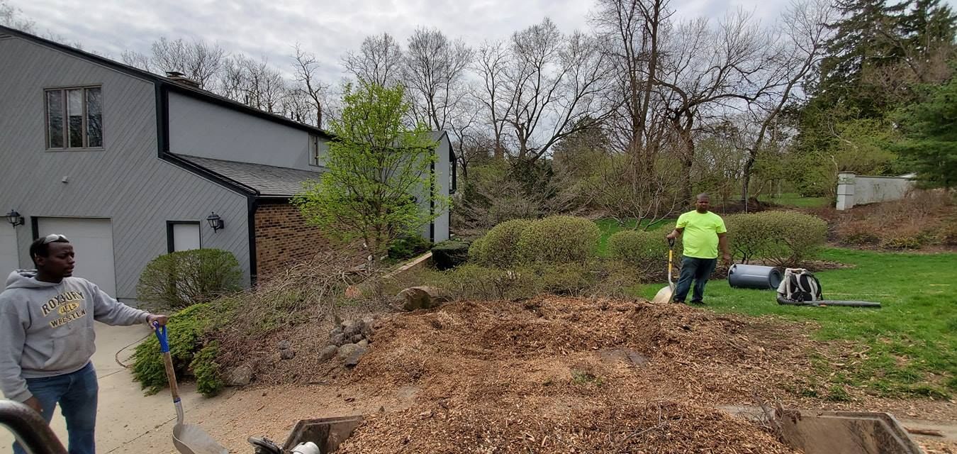 A man is holding a shovel in front of a pile of wood chips.